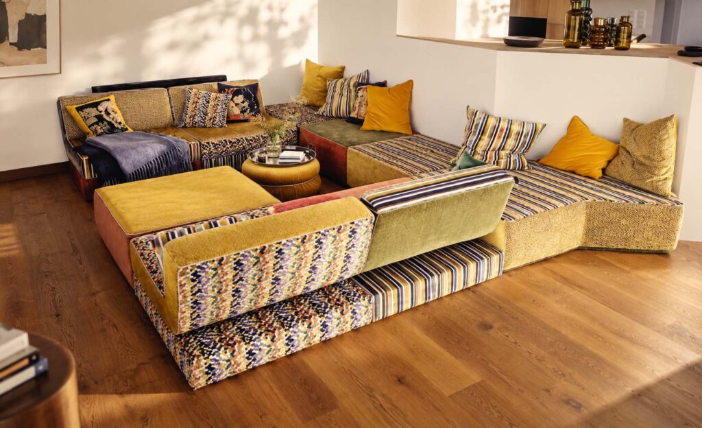 Farbenreiche modulare STRIPE-Wohnlandschaft mit gemusterten und gestreiften Stoffen in einem offenen Wohnraum.